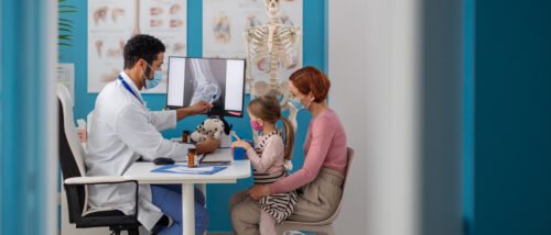 يشرح جراح عظام الأطفال التشخيص لذوي الطفل مستعينًا بالأشعة التشخيصية