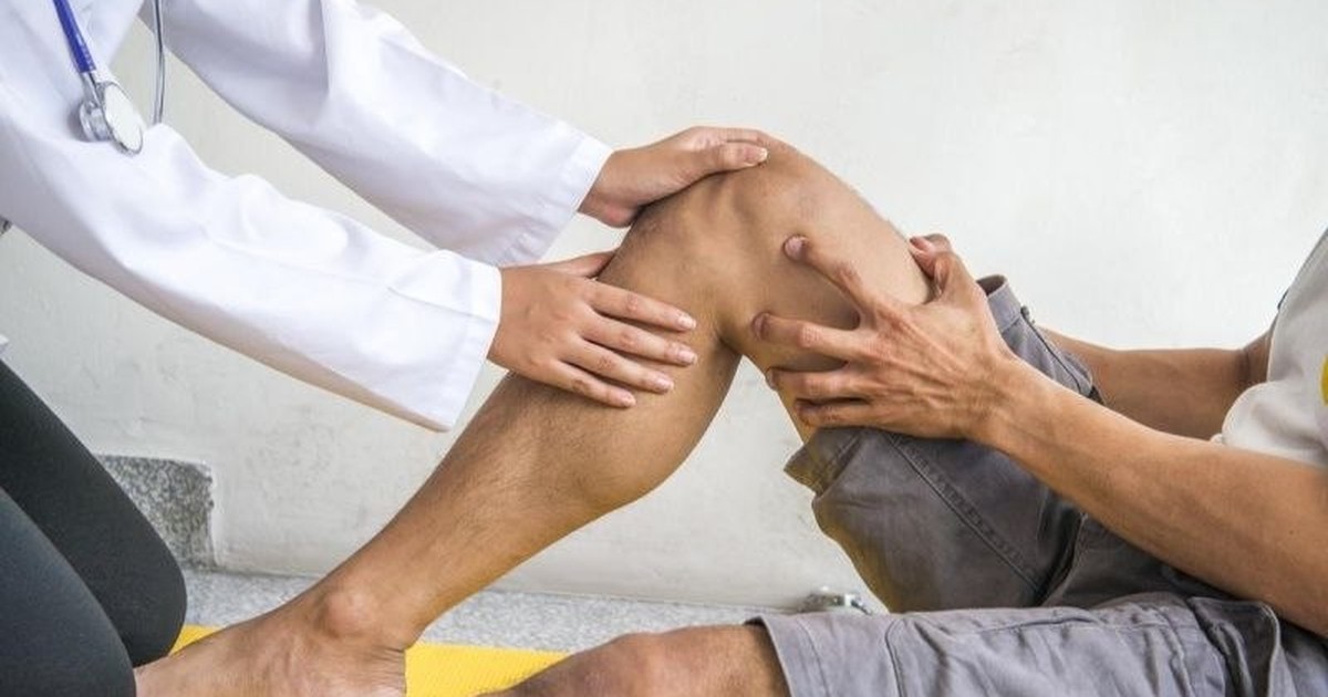 الطبيب يفحص مدى حركة الركبة بعد العملية، يده على الركبة والقدم على المقعد